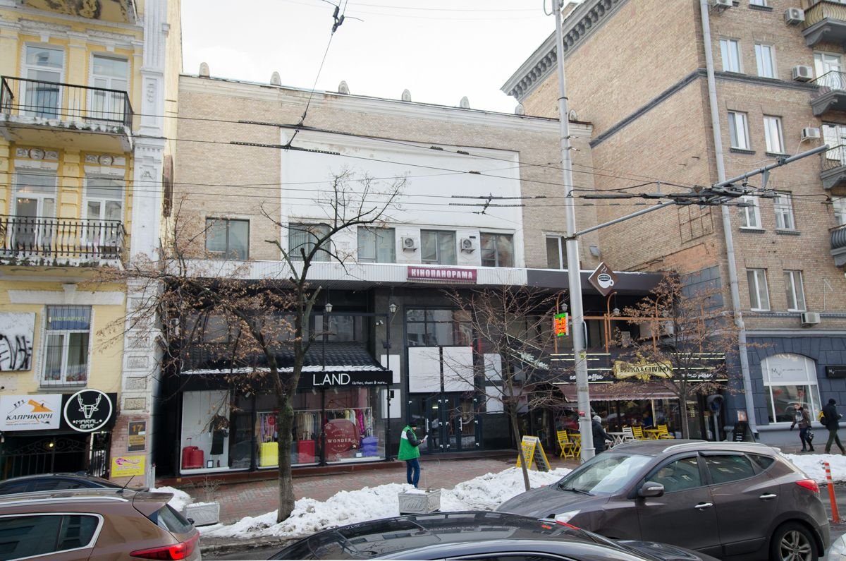 Die Straße zeigt ein Kino mit einem großen Fenster und einem Café im Erdgeschoss.