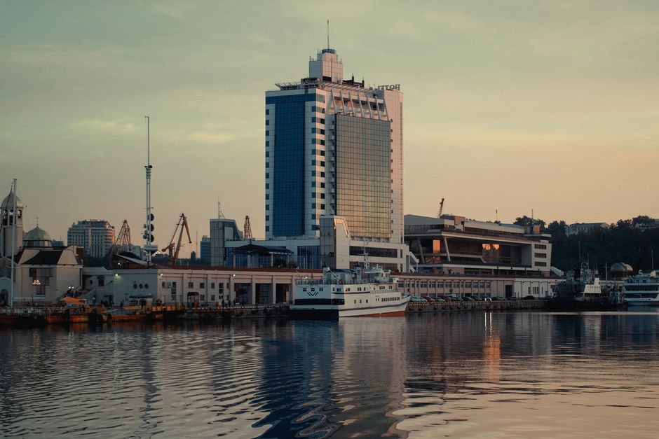 На фотографії видно порт з будівлею та човнами на воді.