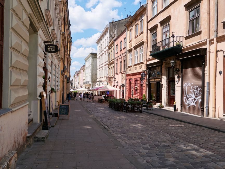 Eine gepflasterte Straße, gesäumt von historischen Gebäuden und Cafés.