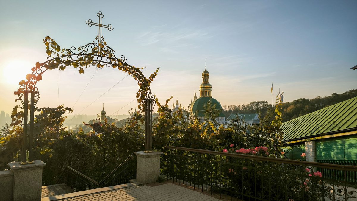 A green domed church is visible in the background, surrounded by grapevines.