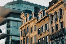 L'immagine mostra un edificio moderno accanto a facciate storiche a Bruxelles.