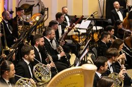 Ein Orchester spielt auf der Bühne in formeller Kleidung.