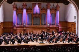 Der Konzertsaal ist mit Musikern und einem Orchester auf der Bühne gefüllt.