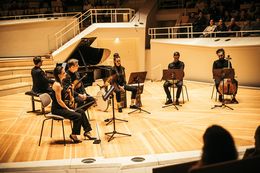 Eine Gruppe von Musikern tritt auf der Bühne mit verschiedenen Instrumenten auf.