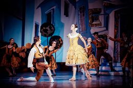 Danzatori in costumi vivaci si esibiscono in un numero coreografico sul palco.
