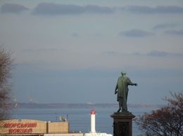 Eine Statue ist sichtbar, die auf den Horizont über dem Meer zeigt.