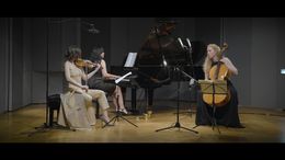 Drei Musikerinnen spielen klassische Musik auf der Bühne mit einem Klavier.