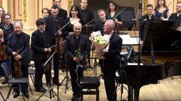 Musicisti con strumenti sono sul palco mentre il pubblico applaude.