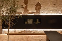L'interno presenta un muro con texture storiche e illuminazione moderna.