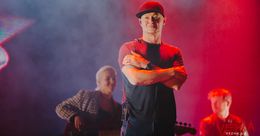 Ein Musiker tritt auf der Bühne mit einem Gitarristen im Hintergrund auf.