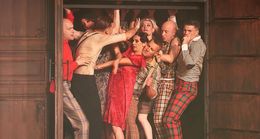 Una performance di danza con un gruppo di artisti in costumi vivaci sul palco.