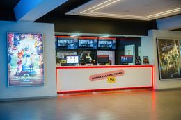 Se ve el mostrador del cine con brillantes carteles de películas en las paredes.