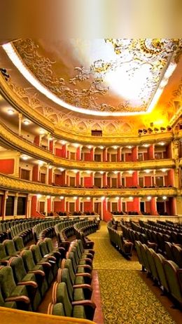 L'interno di un teatro con file di sedili verdi e decorazioni ornate.