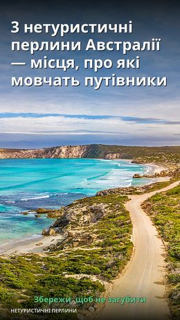 На зображенні видно мальовничу прибережну дорогу, що веде до пляжу з блакитною водою.